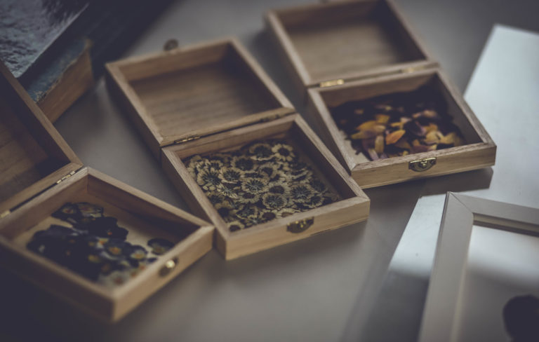 Petites boites en bois contenant des fleurs séchées de santinis blanches